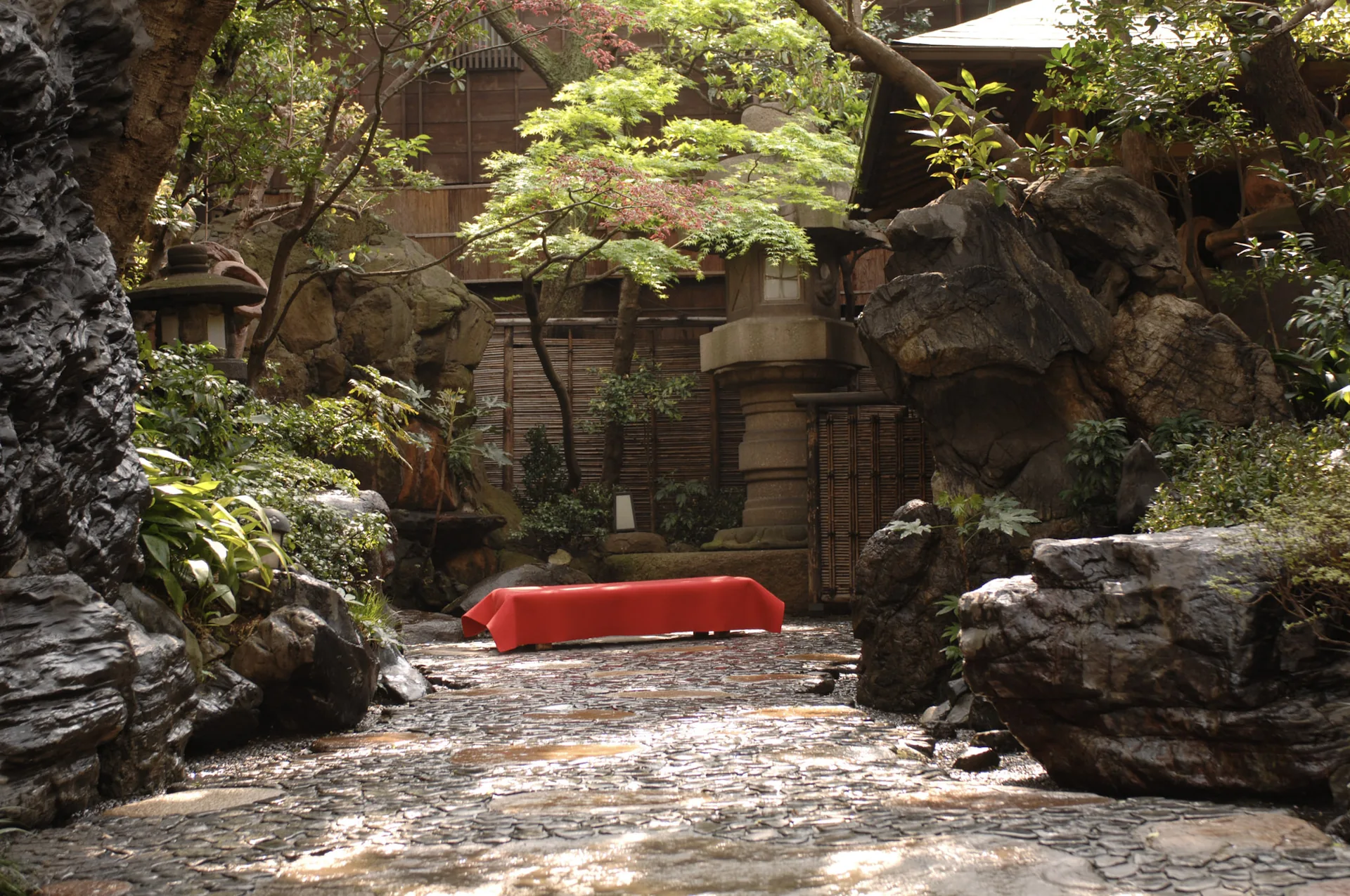 The rock garden at Tsukiji Jisaku with maples and a red bench beside the stone path