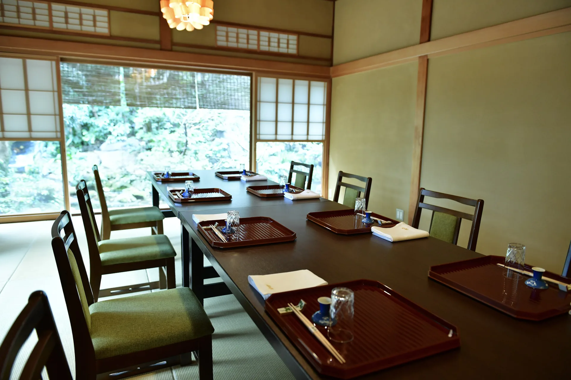 A private dining room at Tsukiji Jisaku laid with lacquer trays, looking onto the garden