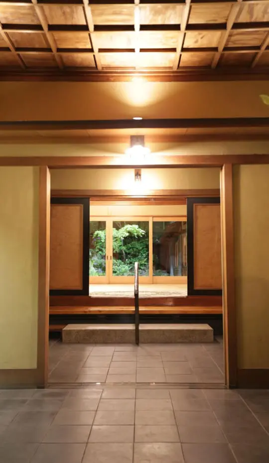 The entrance approach at Tsukiji Jisaku, looking down a lit corridor toward the garden