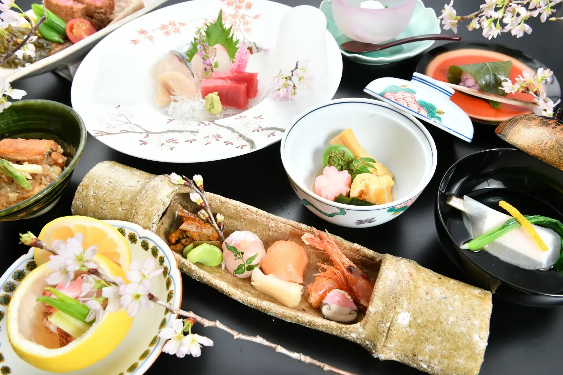 A seasonal kaiseki course at Tsukiji Jisaku served on black lacquer, with sashimi and simmered dishes